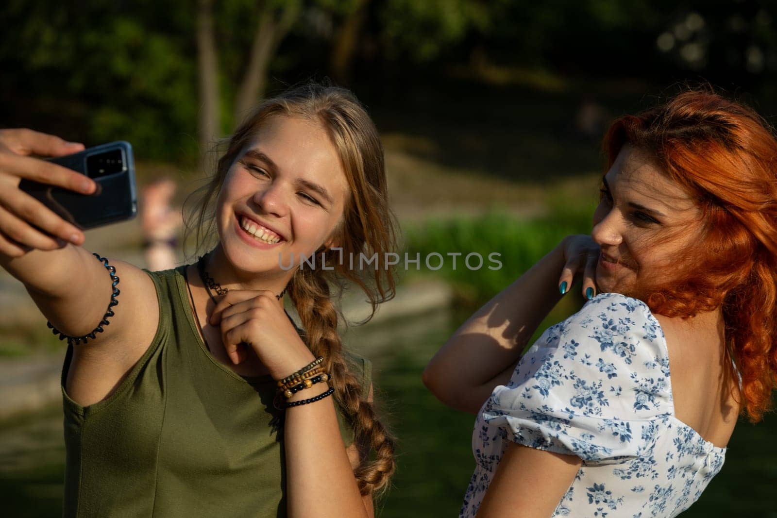 Two friends joyfully capturing a delightful moment with a selfie amidst a beautiful natural setting outside