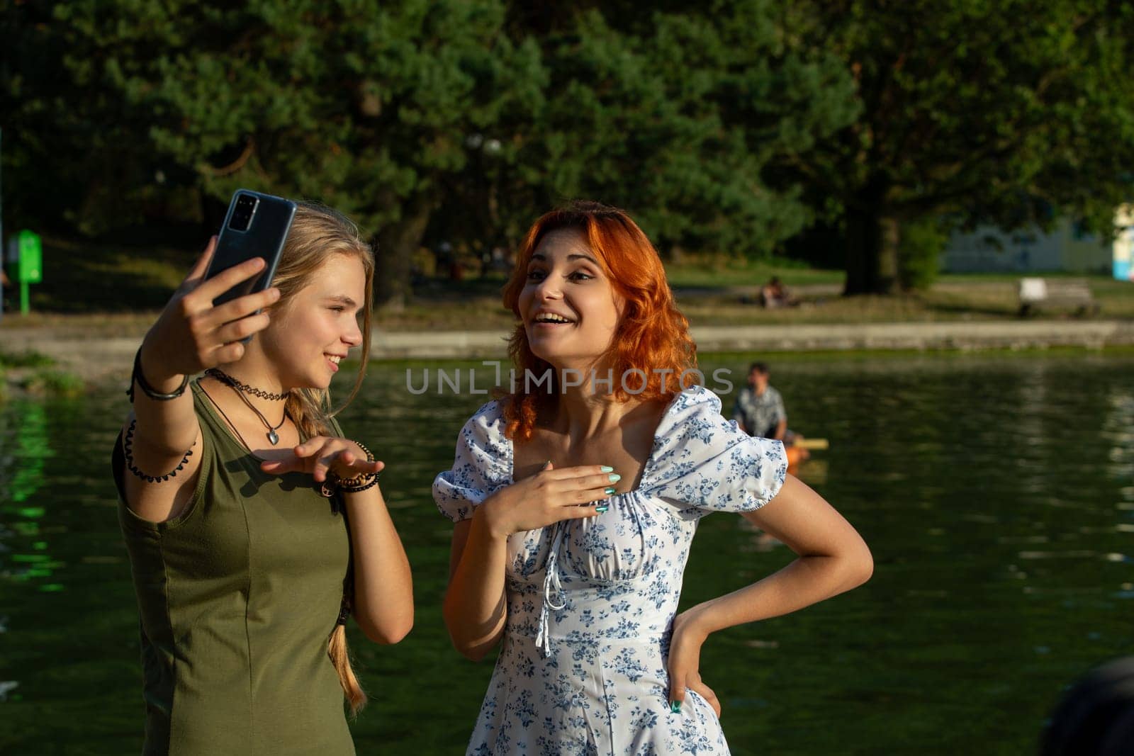 Two cheerful young women joyfully capturing a fun moment near the sparkling water, showcasing their friendship