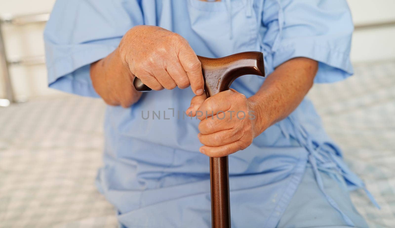 Asian elderly disability woman patient holding walking stick in wrinkled hand at hospital.