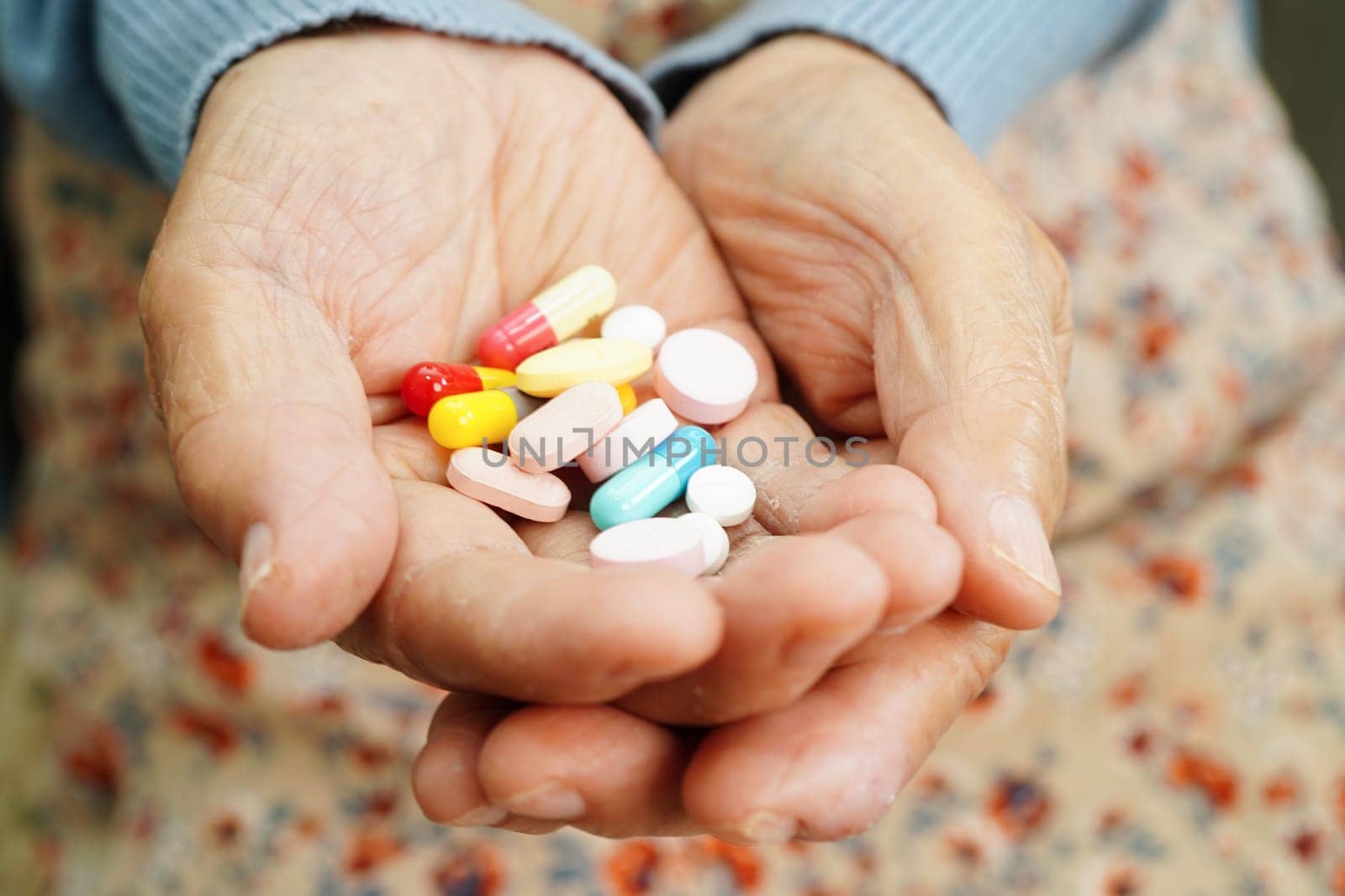 Asian elderly woman holding pill drug in hand, strong healthy medical concept. 