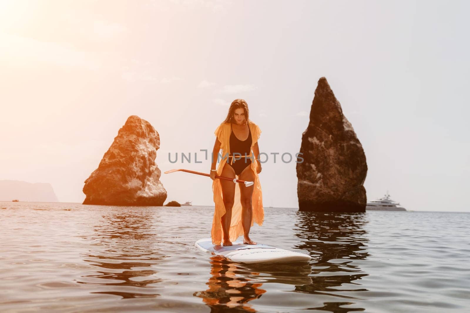 Woman sea sup. Close up portrait of happy young caucasian woman with long hair looking at camera and smiling. Cute woman portrait in bikini posing on sup board in the sea by panophotograph