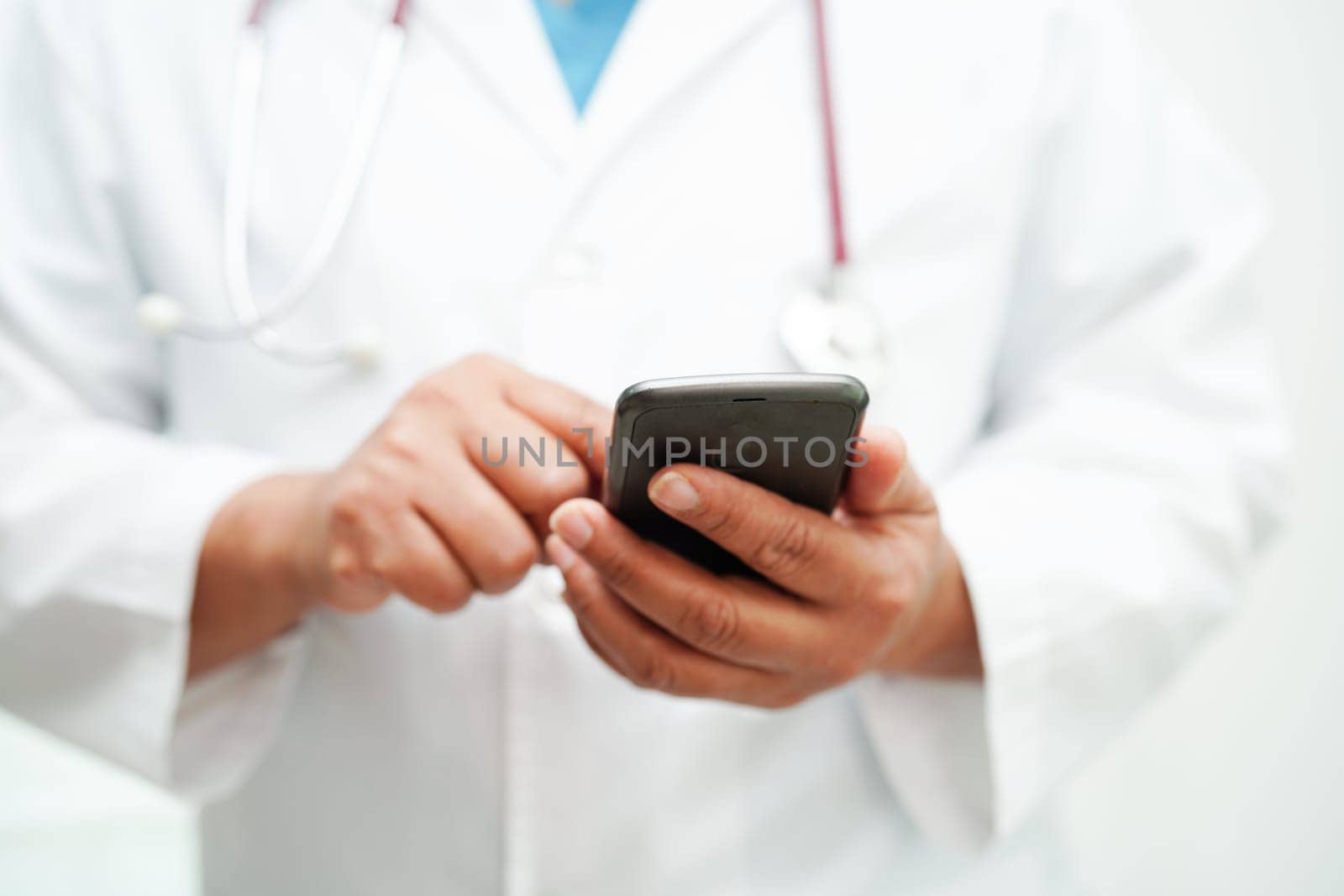 Asian woman doctor holding mobile phone or tablet for search method of treatment patient in hospital.               