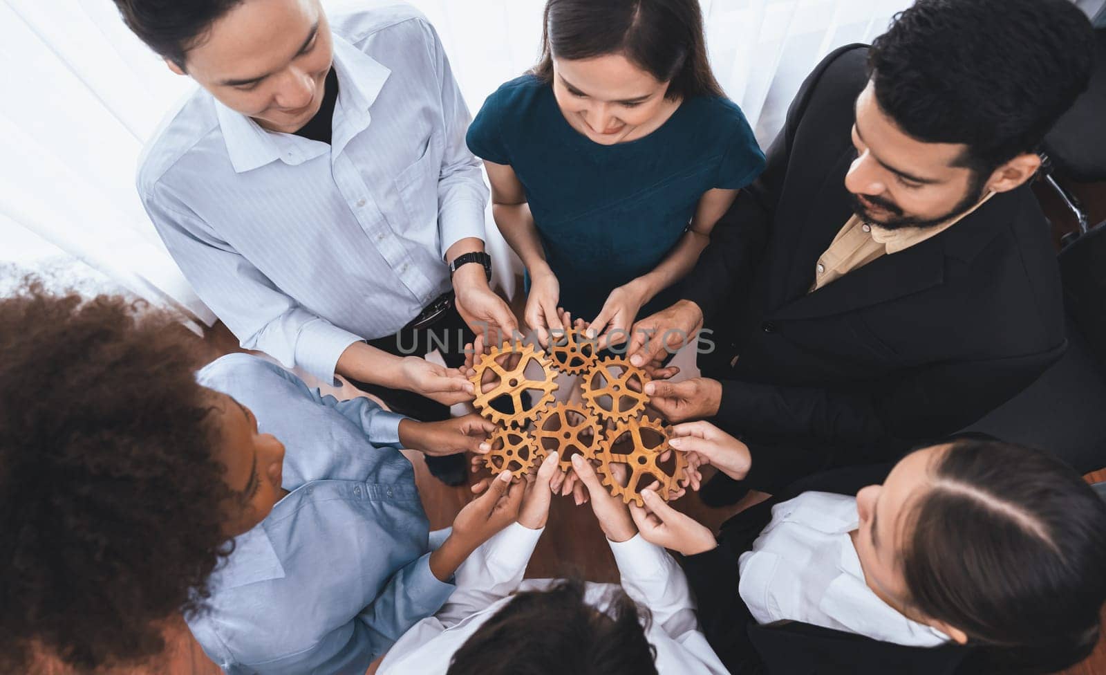 Office worker holding cog wheel as unity and teamwork in corporate workplace concept. Diverse colleague business people showing symbol of visionary system and mechanism for business success. Concord