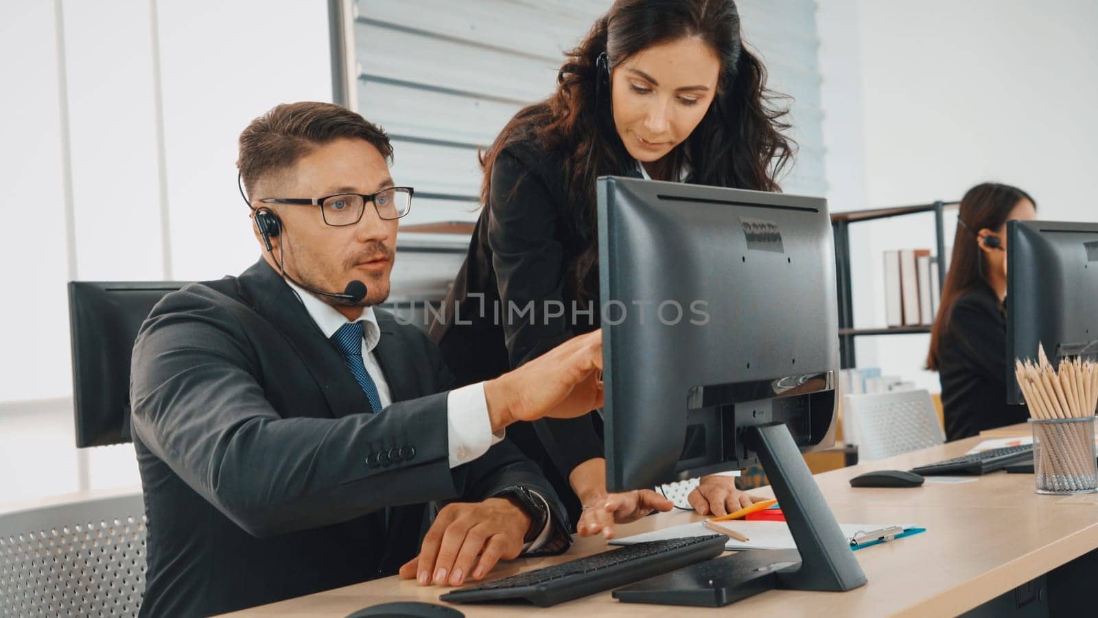 Business people wearing headset working in office to support remote customer or colleague. Call center, telemarketing, customer support agent provide service on telephone video conference call. Jivy