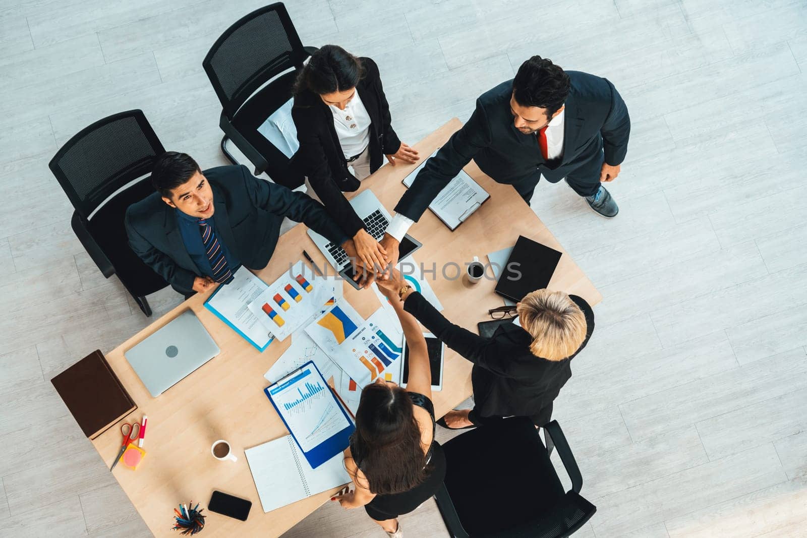 Happy business people celebrate teamwork success together with joy at office table shot from top view . Young businessman and businesswoman workers express cheerful victory show unity support . Jivy