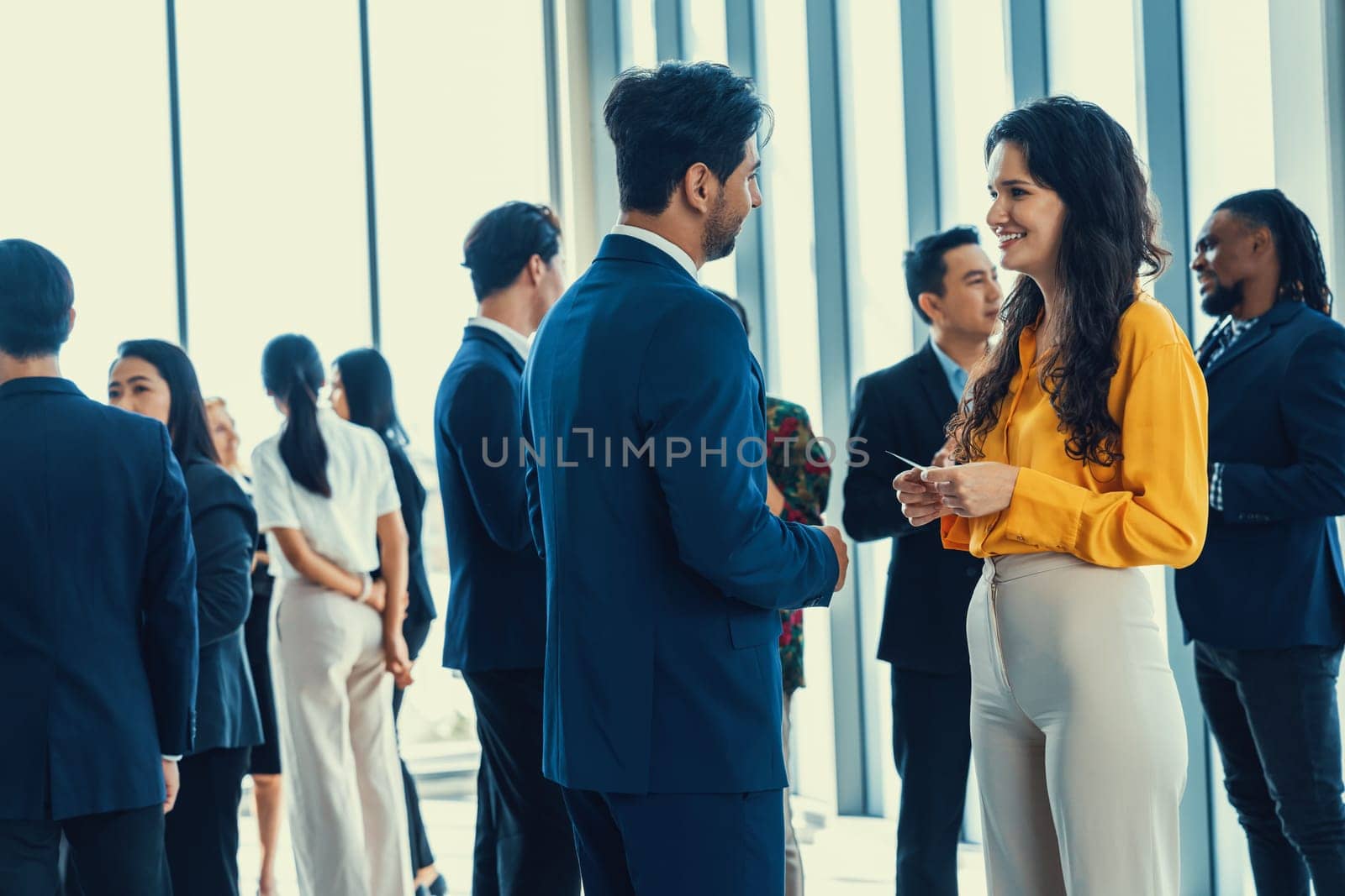 Businessman discussing with female leader about financial project intentionally while standing rounded with business people exchanging financial experience. Side view. Office hallway. Intellectual.