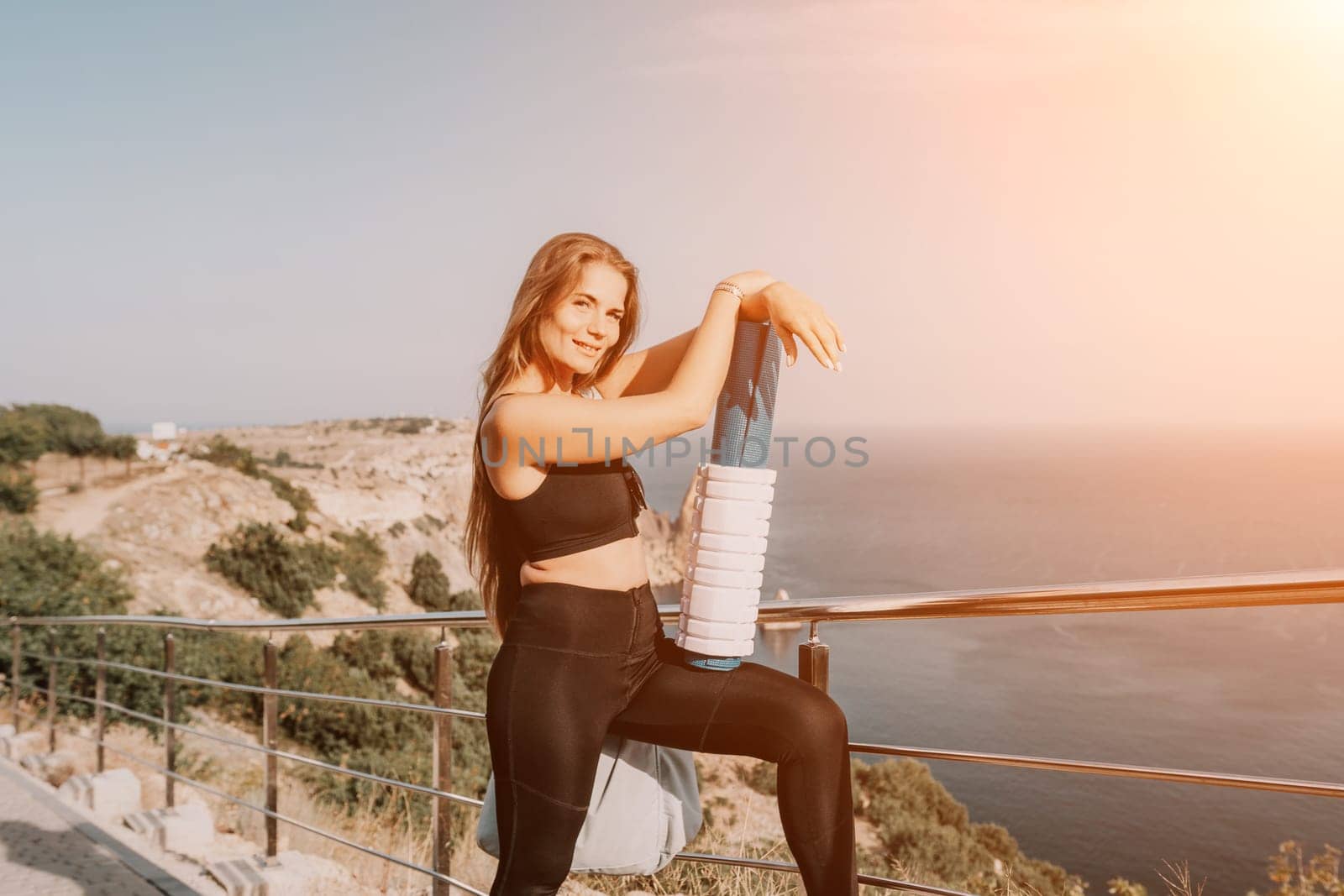 Fitness woman sea. Outdoor workout on yoga mat roller in park near to ocean beach. Female fitness pilates yoga routine concept. Healthy lifestyle. Happy fit woman exercising with rubber band in park. by panophotograph