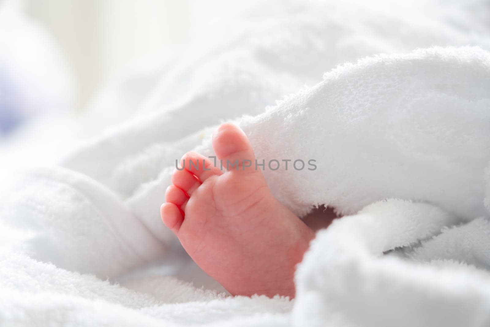 After the bath: infant's foot shyly emerging from soft white comfort by Mariakray
