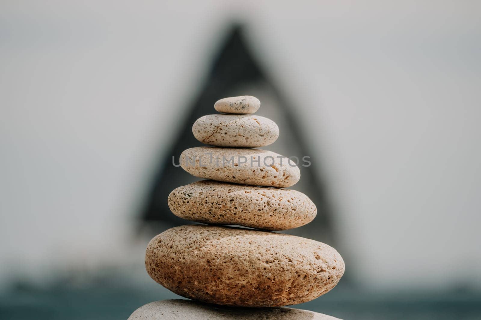 Pyramid stones on the seashore with warm sunset on the sea background. Happy holidays. Pebble beach, calm sea, travel destination. Concept of happy vacation on the sea, meditation, spa, calmness.