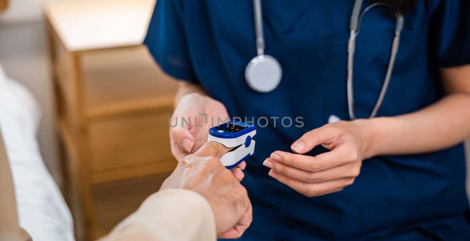 Young woman putting oximeter of finger aged adult patient by Sorapop