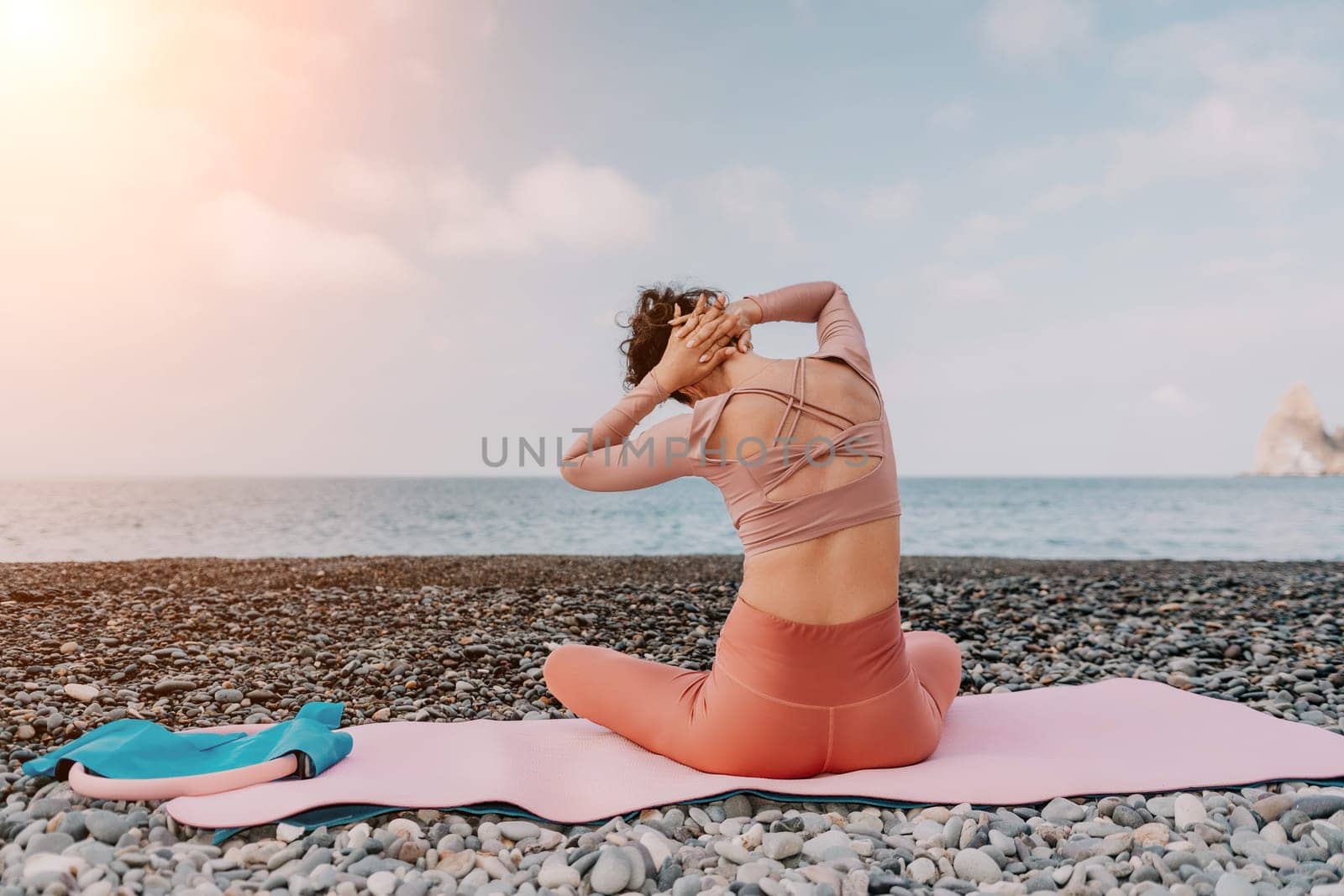 Woman sea pilates. Sporty happy middle aged woman practicing fitness on beach near sea, smiling active female training with ring on yoga mat outside, enjoying healthy lifestyle, harmony and meditation by panophotograph