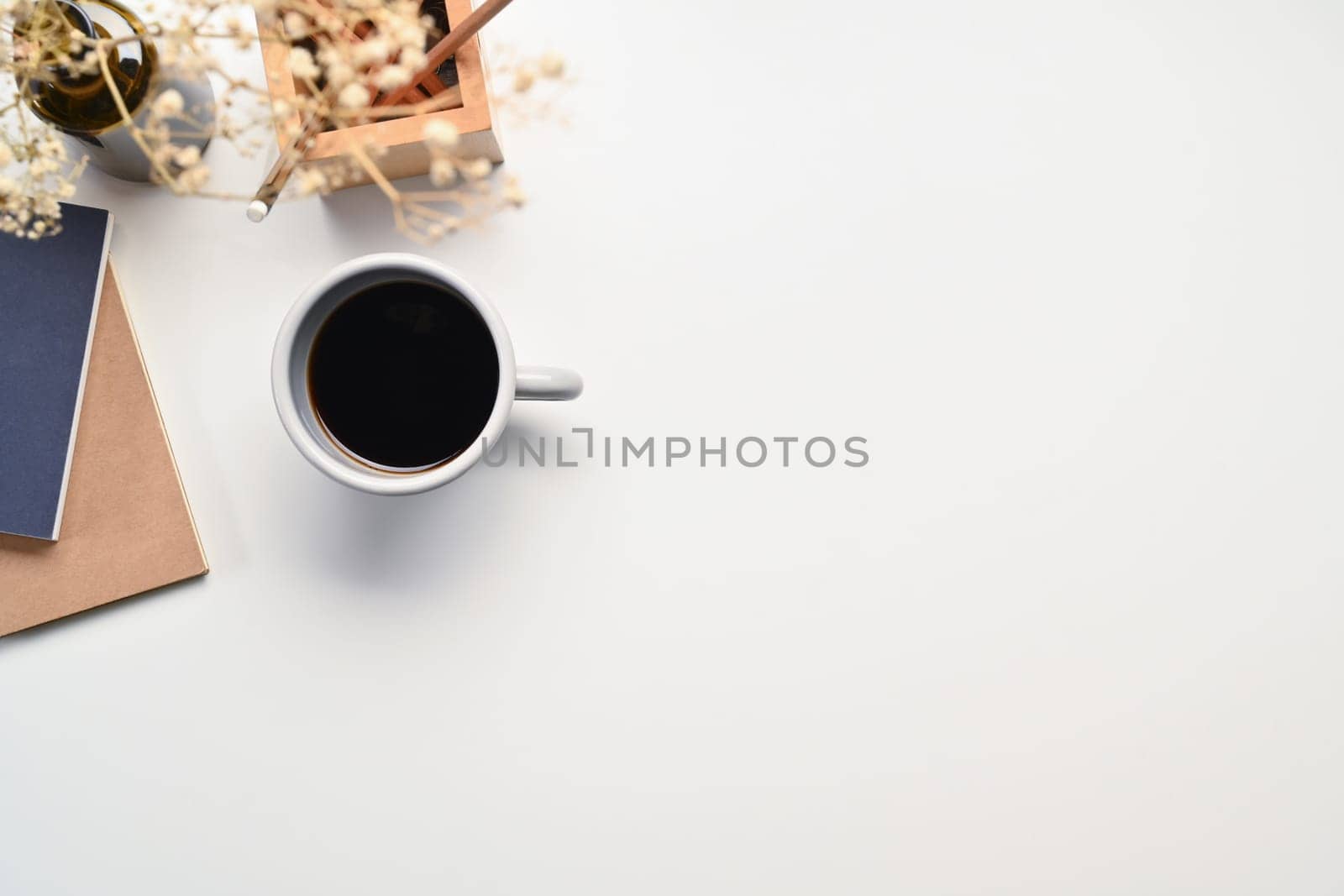 Top view of a coffee cup, notebooks and dried flowers on white table. Space for text advertising text message.