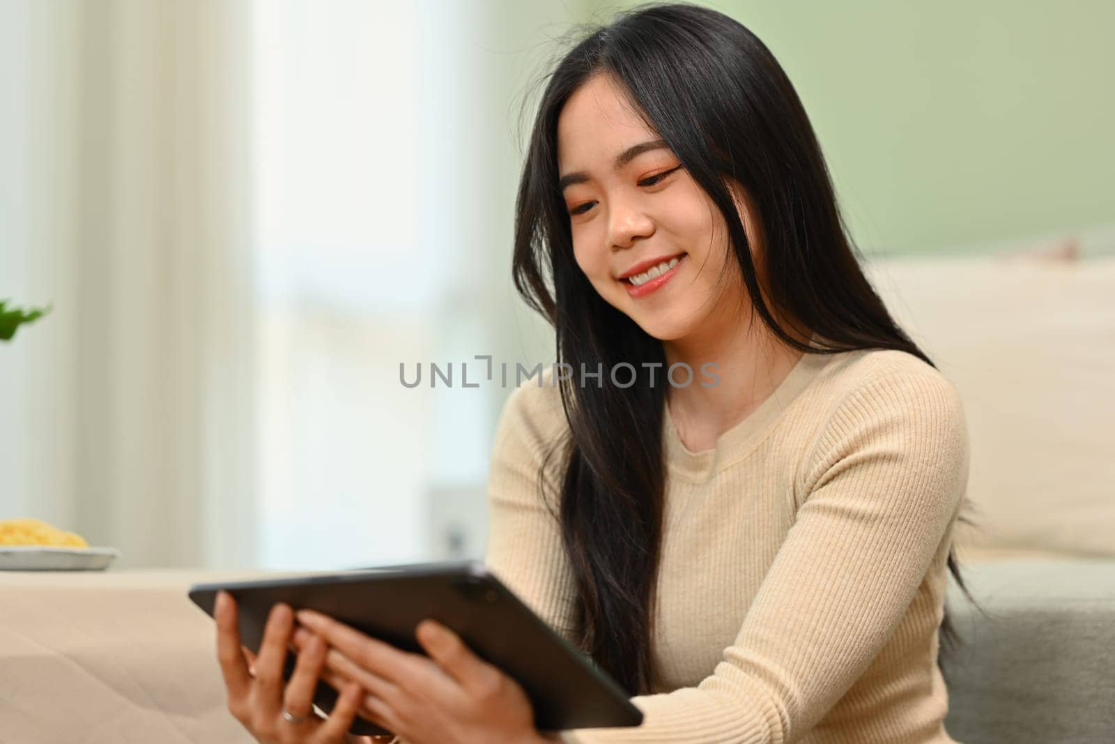 Pleased, smiling young woman using digital tablet in living room. Technology, people and lifestyle concept by prathanchorruangsak