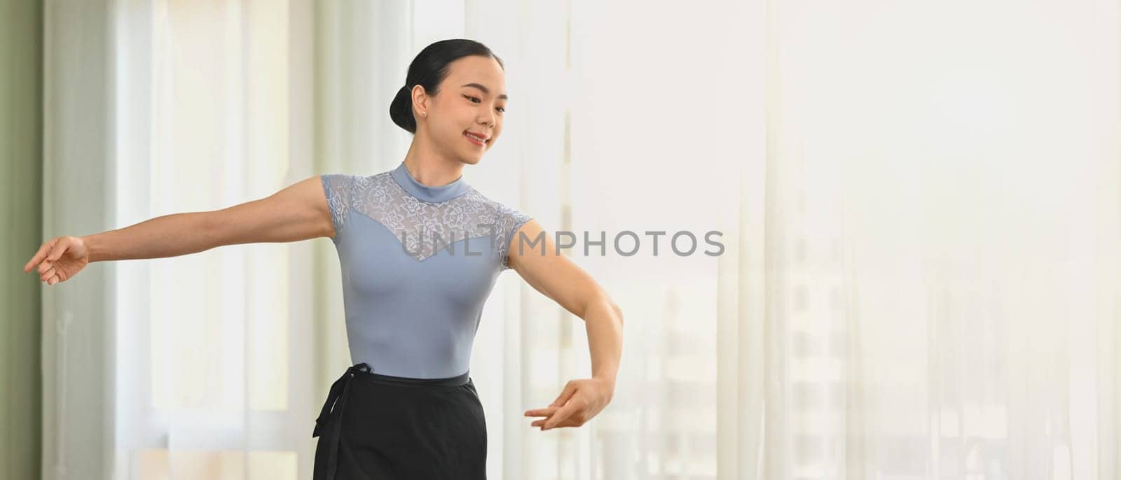 Graceful ballerina practicing dance moves in bright studio. Dance, art, education and flexibility concept by prathanchorruangsak