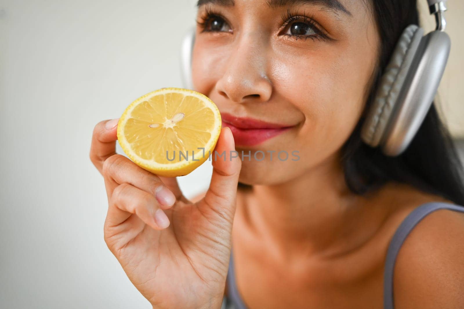 Close up beauty woman in headphone holding half lemon. Dieting and healthy lifestyle concept.