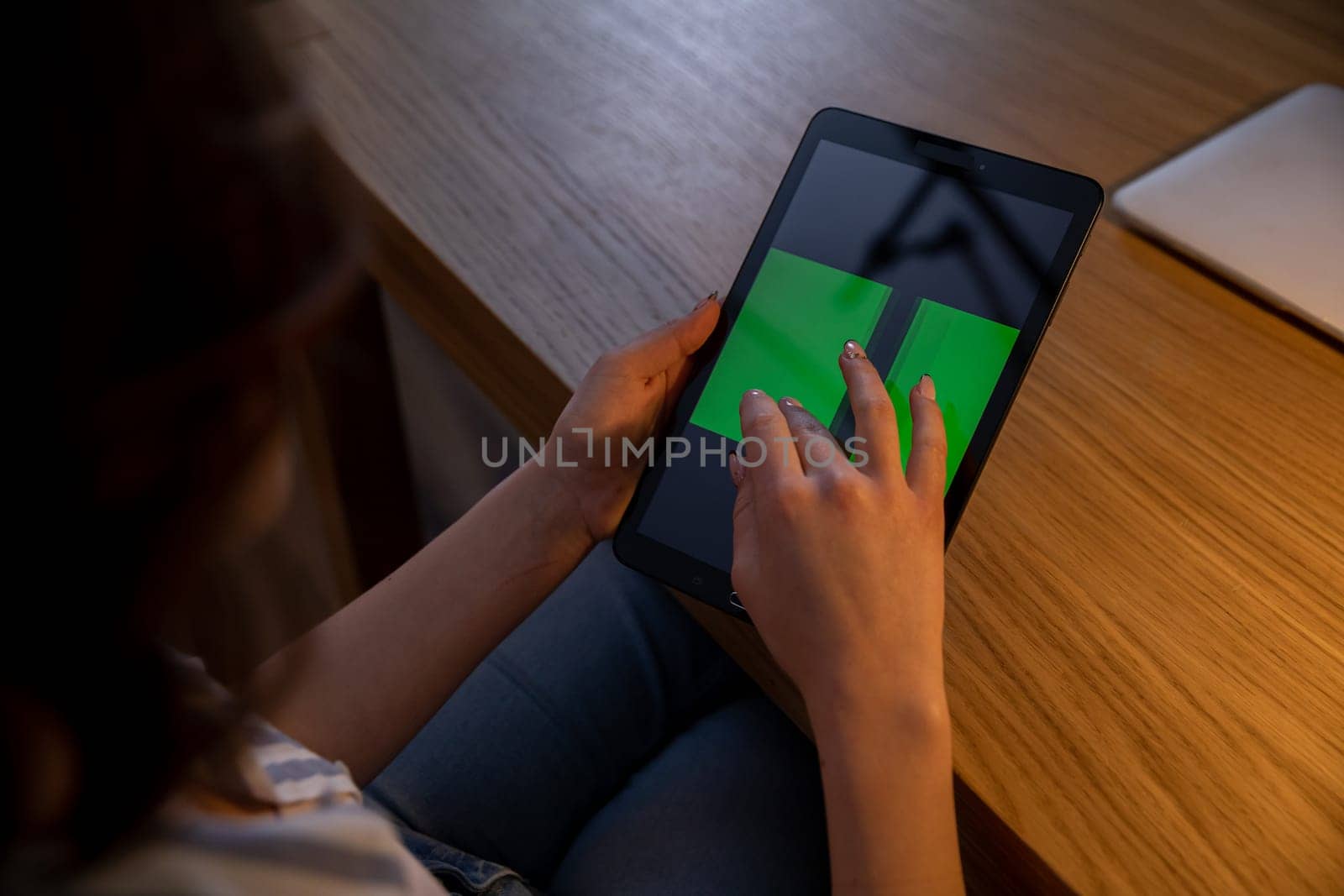 A person interacts with a tablet featuring vibrant green elements in a cozy and inviting environment