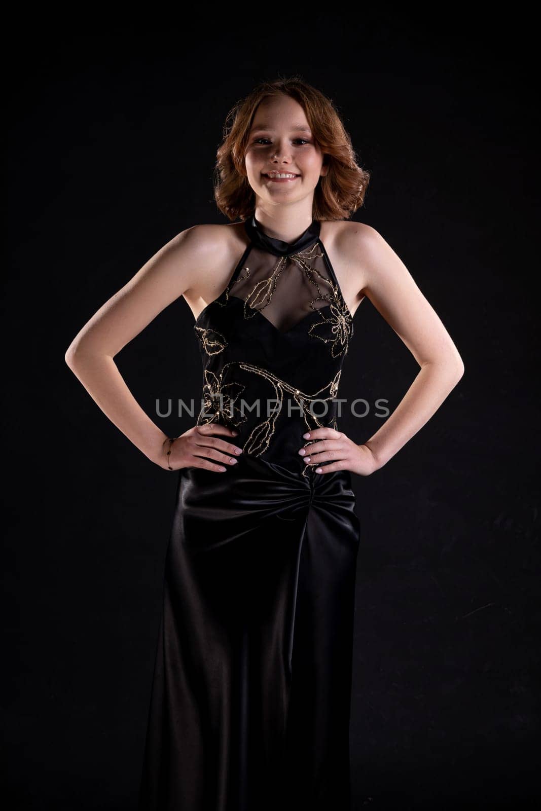 A poised and elegant model is beautifully showcasing a stunning black evening gown set against a dark backdrop