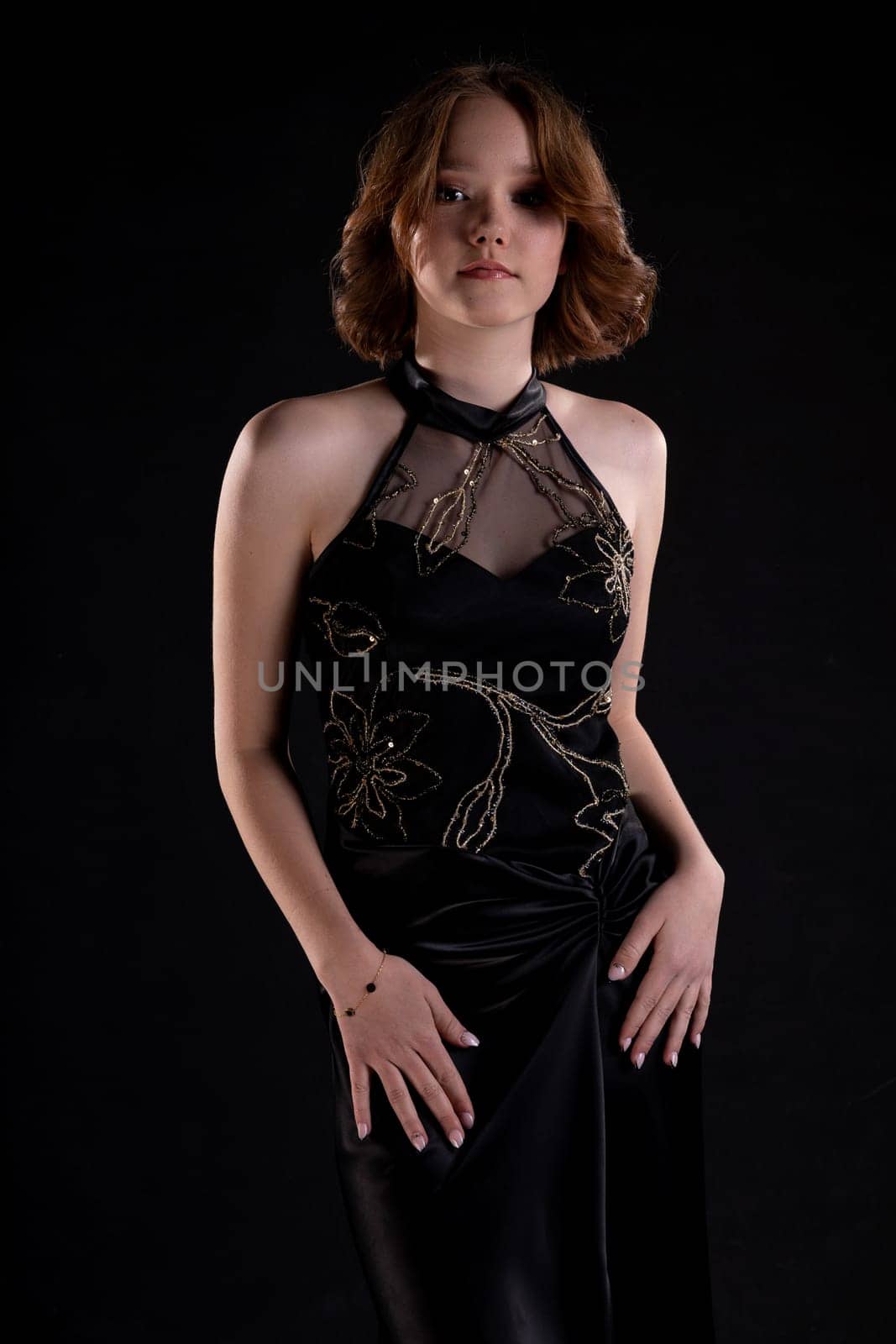 A sophisticated model elegantly posing in a stylish black dress set against a dark backdrop, exuding pure elegance