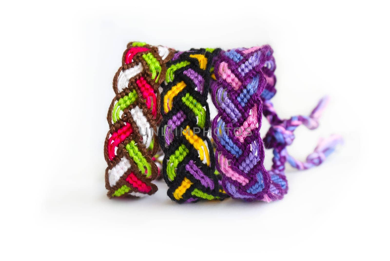 Multicolored woven DIY friendship bracelets handmade of embroidery bright thread with knots isolated on white background