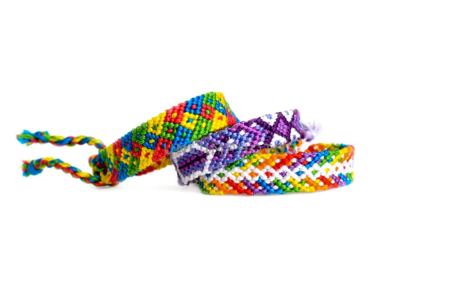 Multicolored woven DIY friendship bracelets handmade of embroidery bright thread with knots isolated on white background