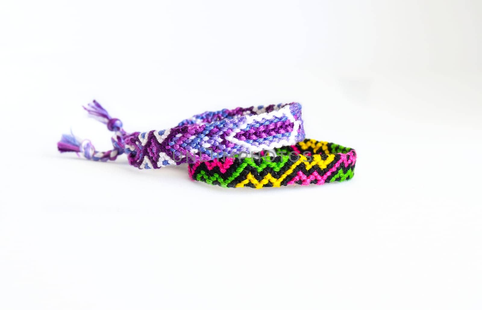 Multicolored woven DIY friendship bracelets handmade of embroidery bright thread with knots isolated on white background