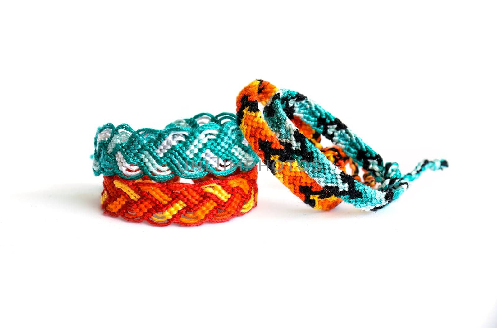 Multicolored woven DIY friendship bracelets handmade of embroidery bright thread with knots isolated on white background