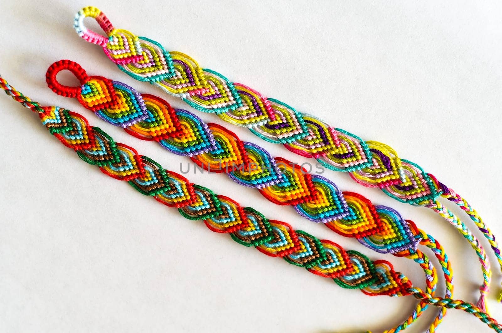 Multicolored woven DIY friendship bracelets handmade of embroidery bright thread with knots isolated on white background