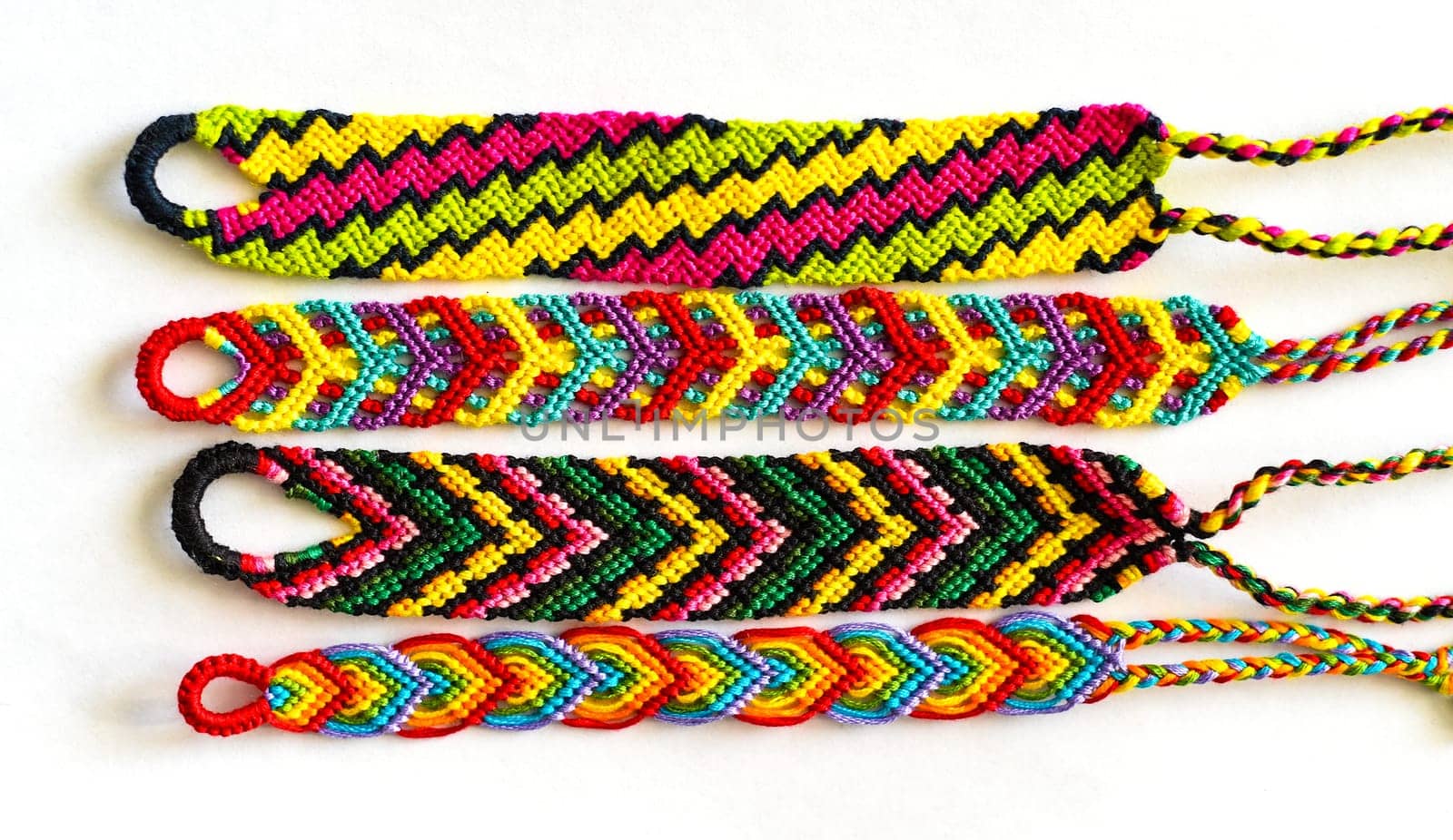 Multicolored woven DIY friendship bracelets handmade of embroidery bright thread with knots isolated on white background