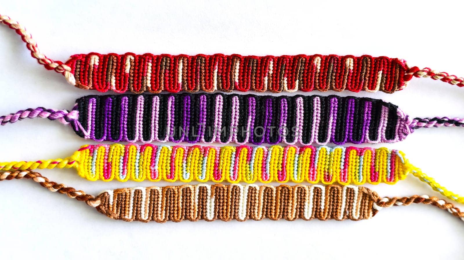 Multicolored woven DIY friendship bracelets handmade of embroidery bright thread with knots isolated on white background