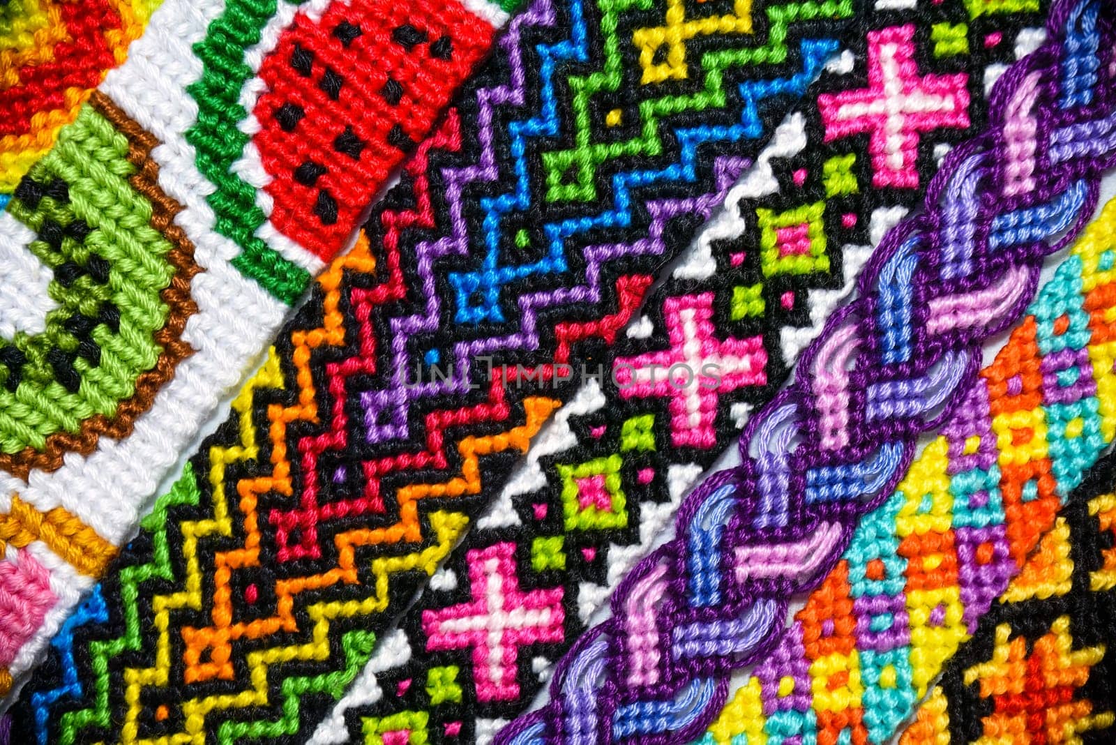 Multicolored woven DIY friendship bracelets handmade of embroidery bright thread with knots isolated on white background