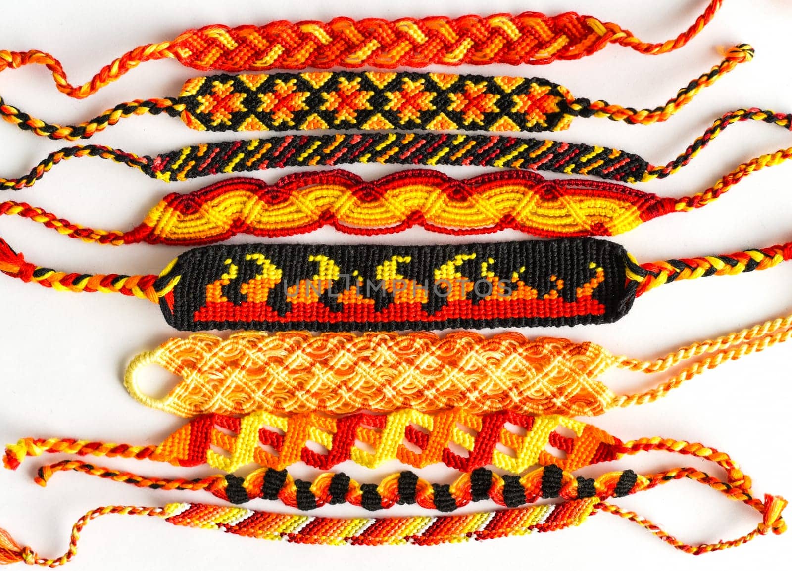 Woven DIY friendship bracelets handmade of embroidery floss with knots. Fire colors