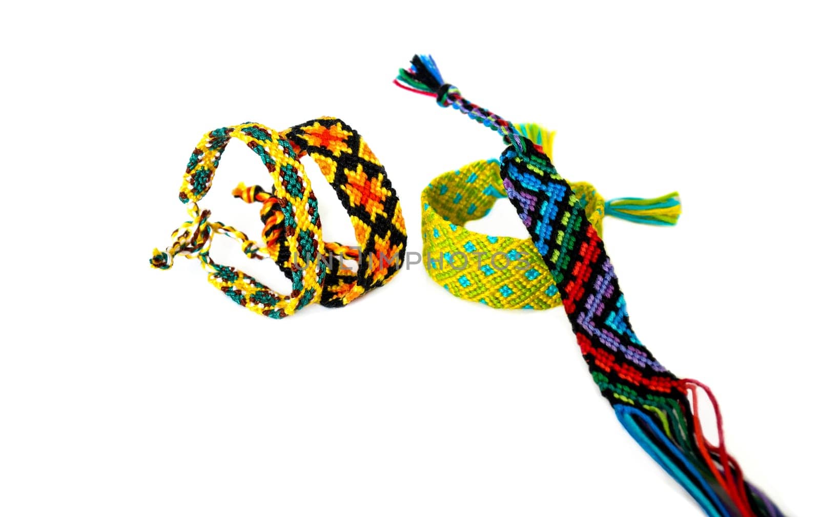 Multicolored woven DIY friendship bracelets handmade of embroidery bright thread with knots isolated on white background