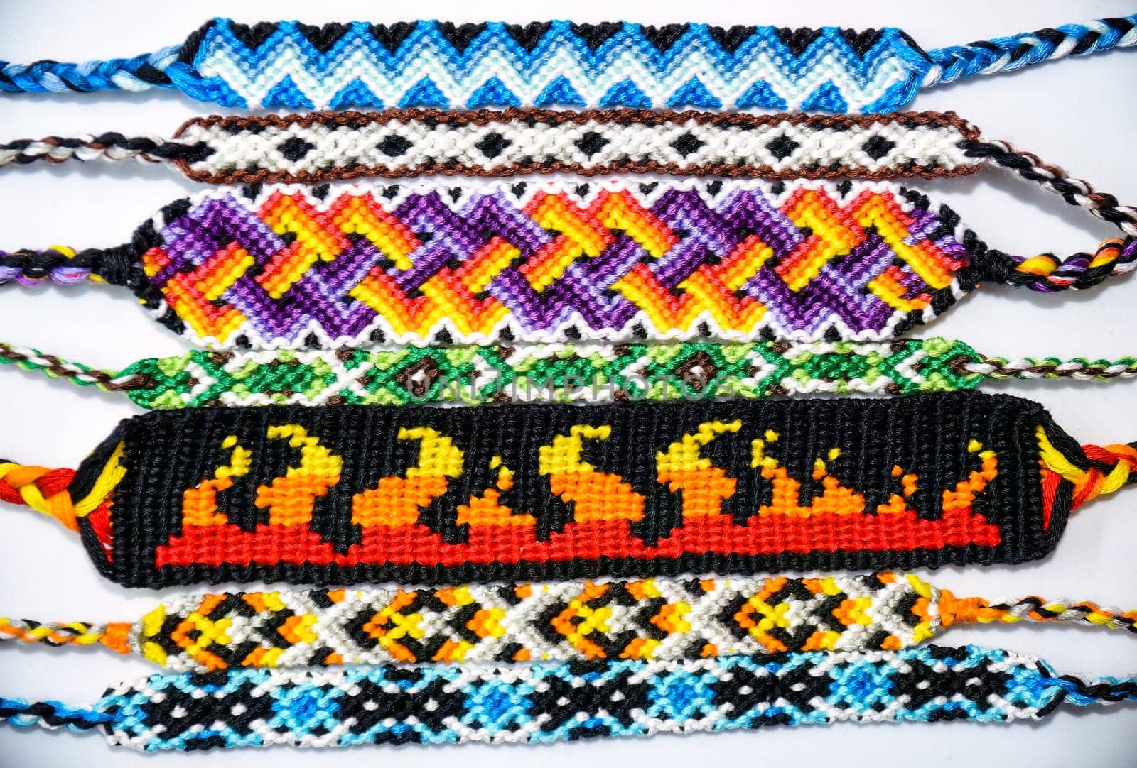 Multicolored woven DIY friendship bracelets handmade of embroidery bright thread with knots isolated on white background