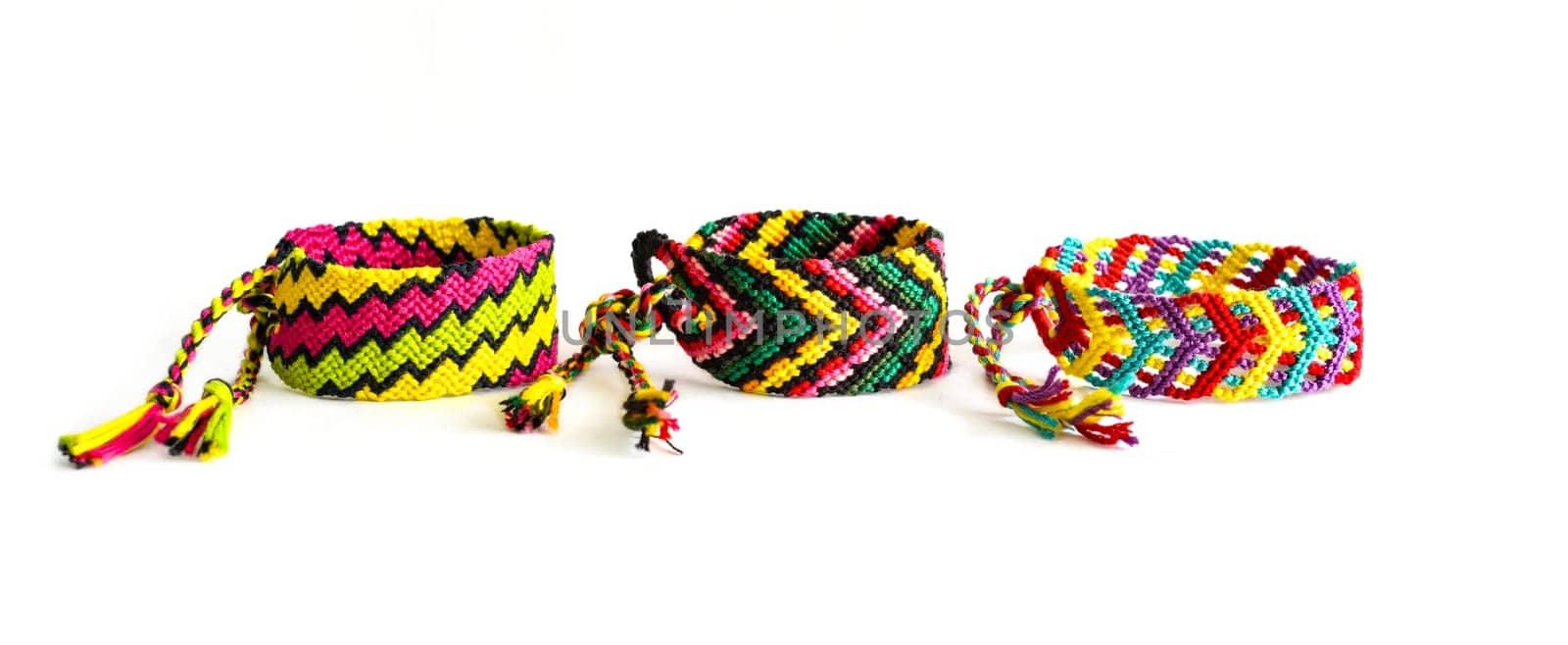 Multicolored woven DIY friendship bracelets handmade of embroidery bright thread with knots isolated on white background