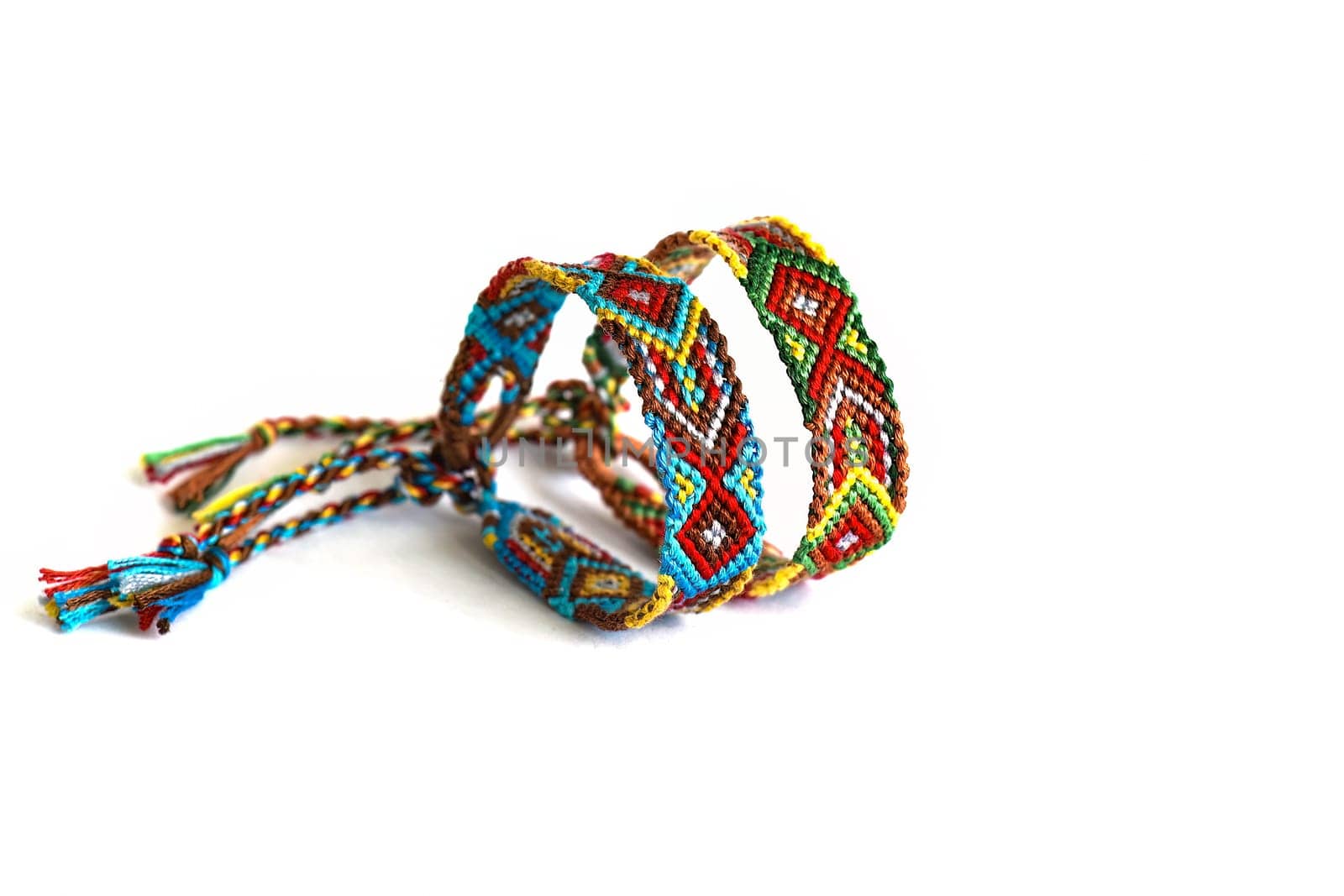 Multicolored woven DIY friendship bracelets handmade of embroidery bright thread with knots isolated on white background