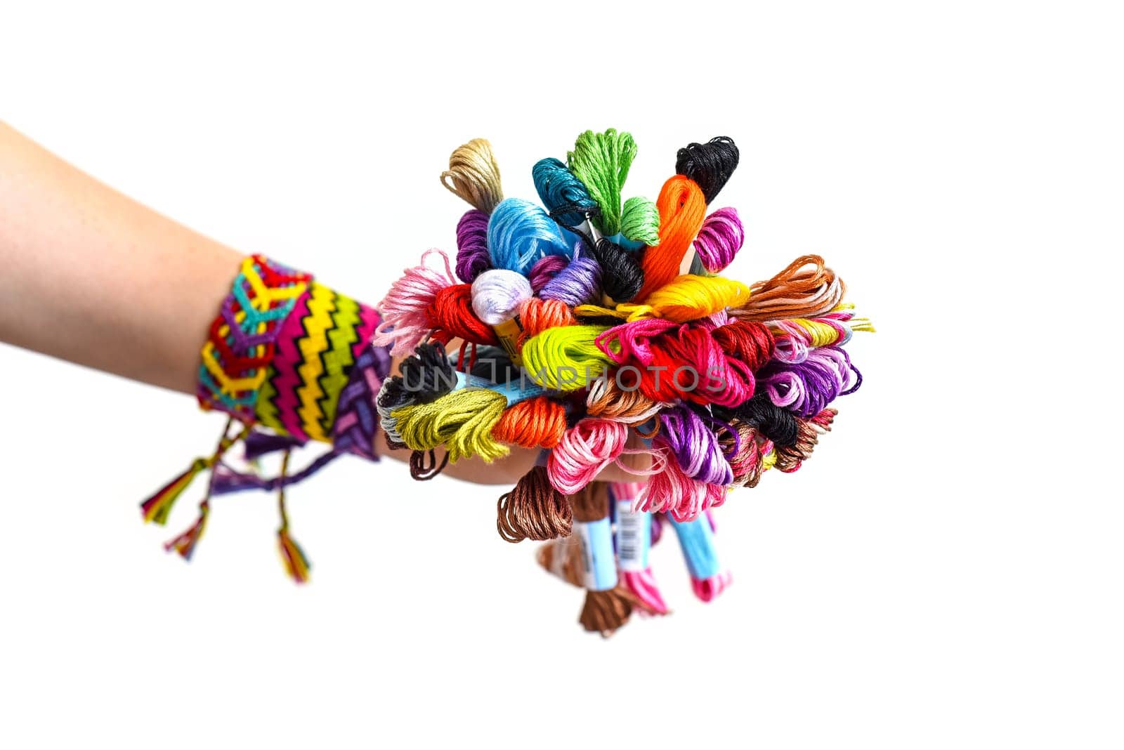 Many embroidery thread for friendship bracelets in hand. Female hand with handmade bracelets on wrists. White background with copy space