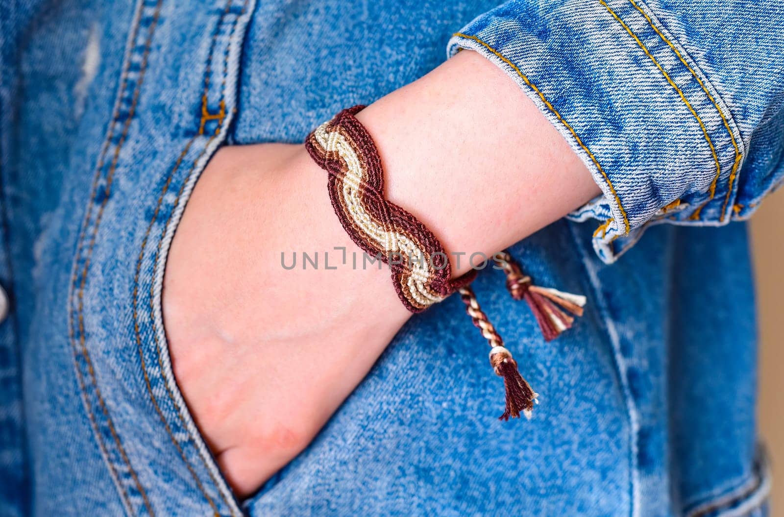 DIY woven tied friendship bracelet on a wrist. Hand in pocket