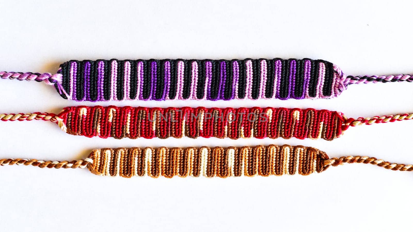 Multicolored woven DIY friendship bracelets handmade of embroidery bright thread with knots isolated on white background