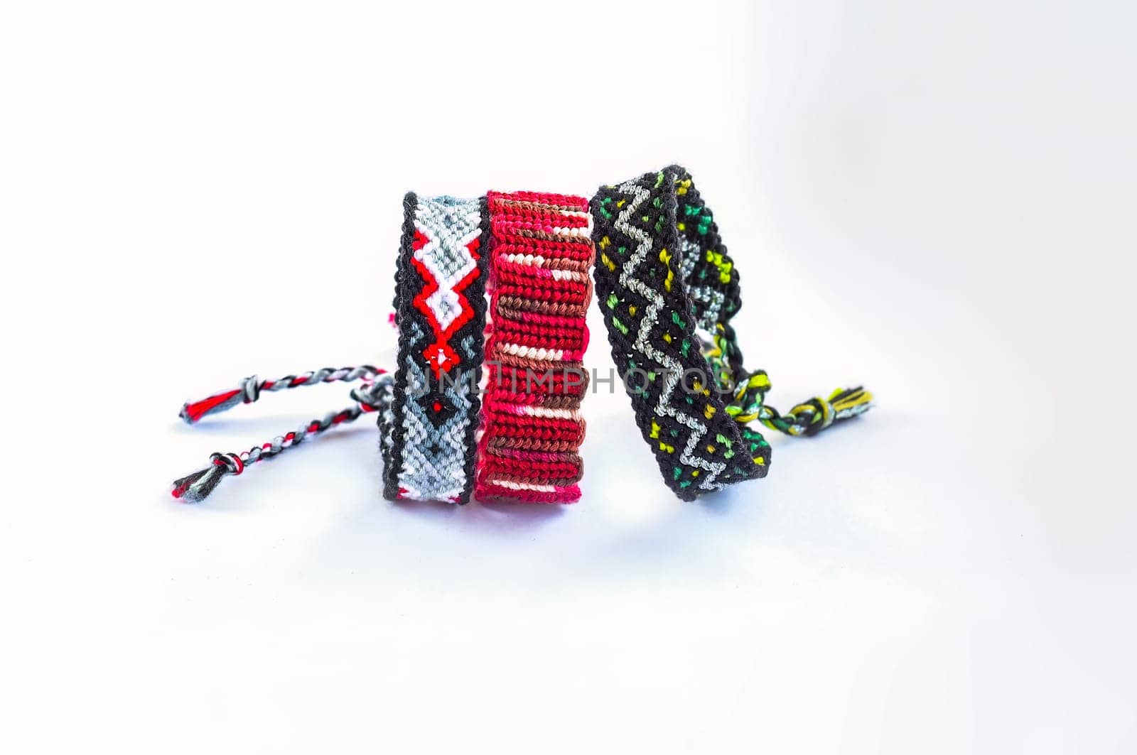 Multicolored woven DIY friendship bracelets handmade of embroidery bright thread with knots isolated on white background