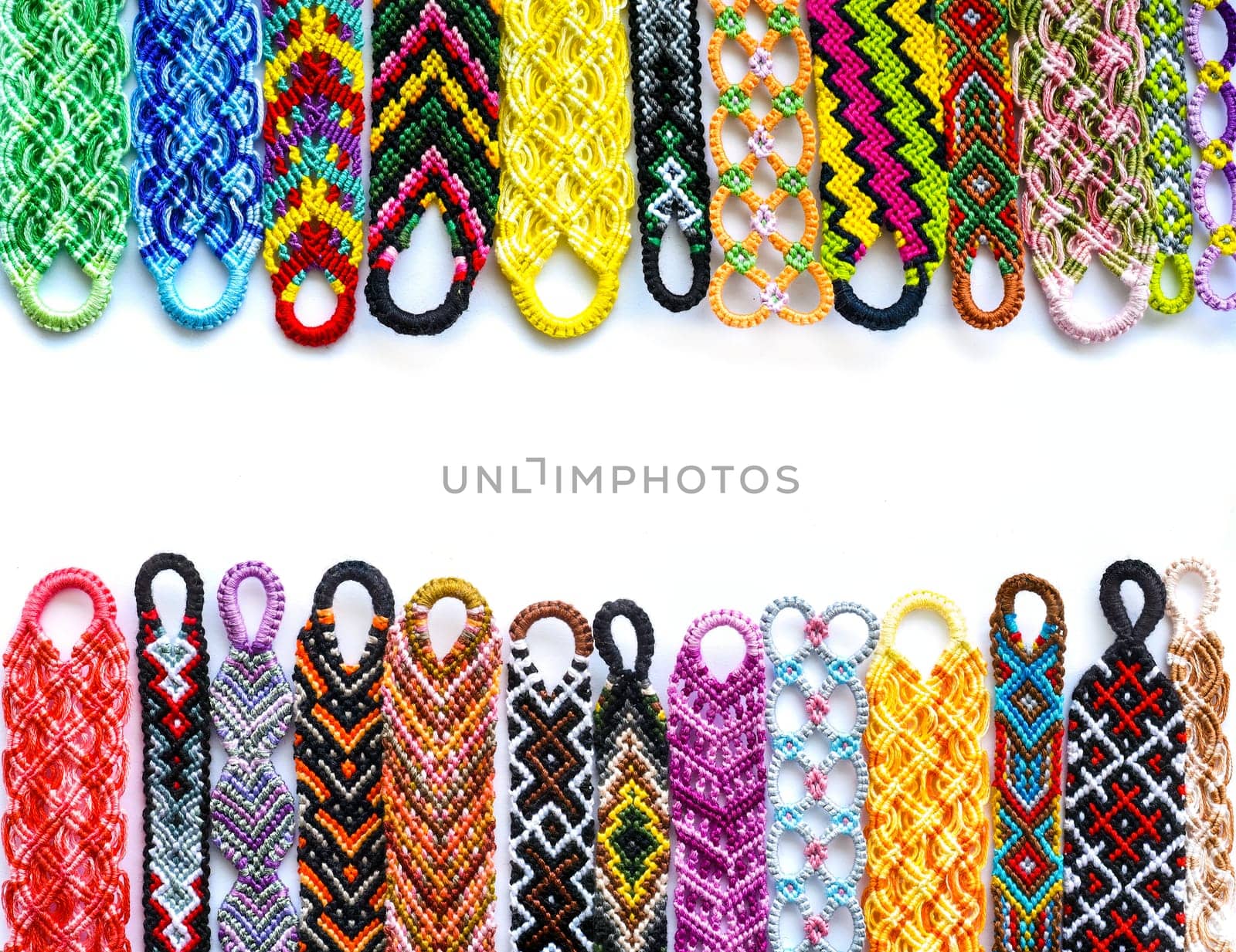 Woven DIY friendship bracelets handmade of embroidery bright thread with knots on white background.