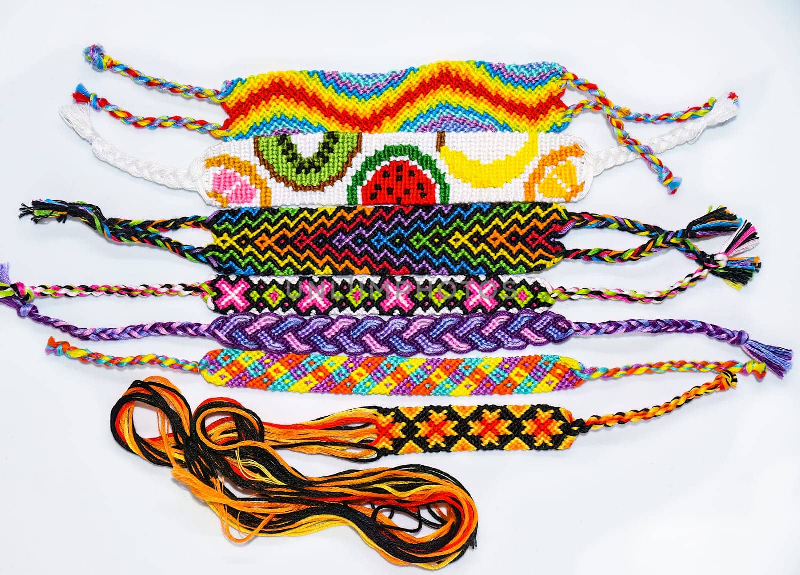 Multicolored woven DIY friendship bracelets handmade of embroidery bright thread with knots isolated on white background