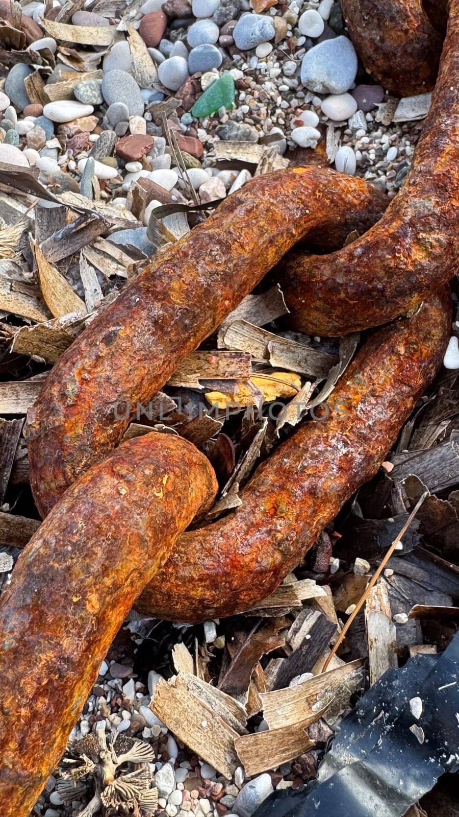 Close-up of a large rusty chain on a pebble beach. High quality photos