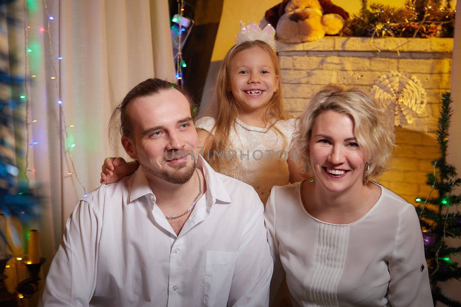A cheerful family gathers indoors to celebrate Christmas, surrounded by decorations and a glowing Christmas tree.
