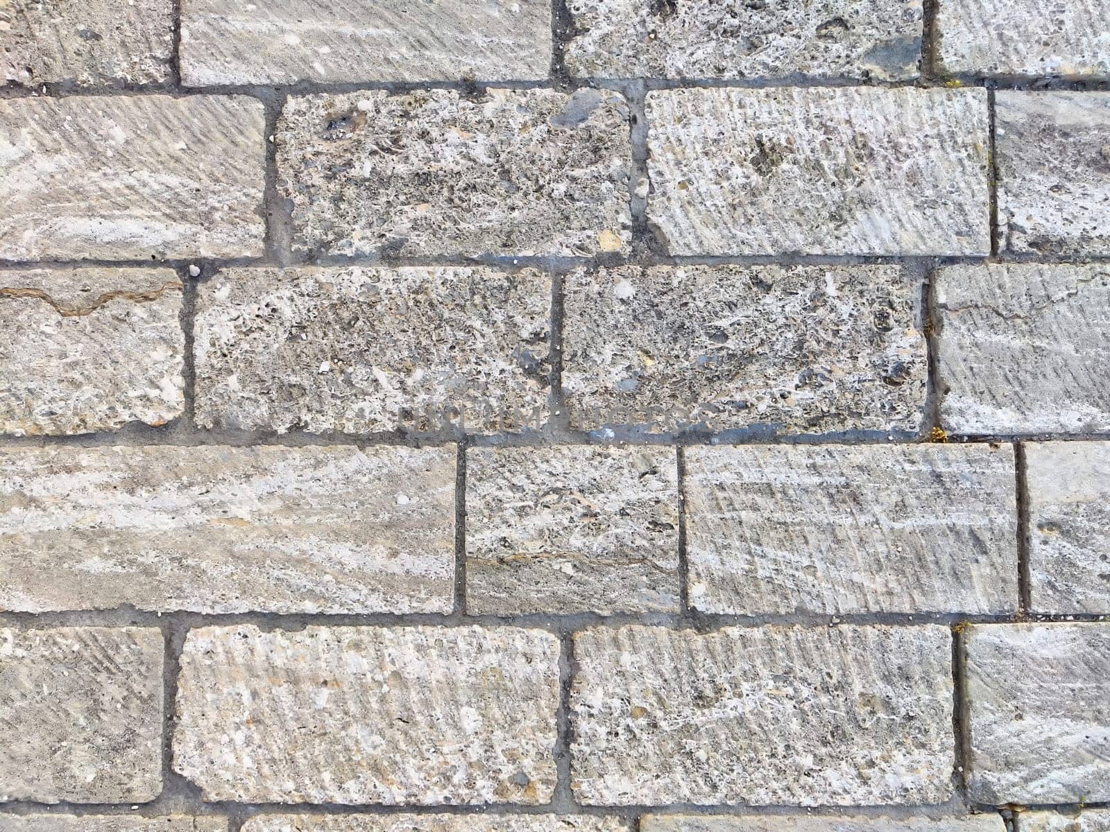 This textured stone background features gray bricks arranged in a structured pattern, providing a clean, minimalistic space for text or designs.