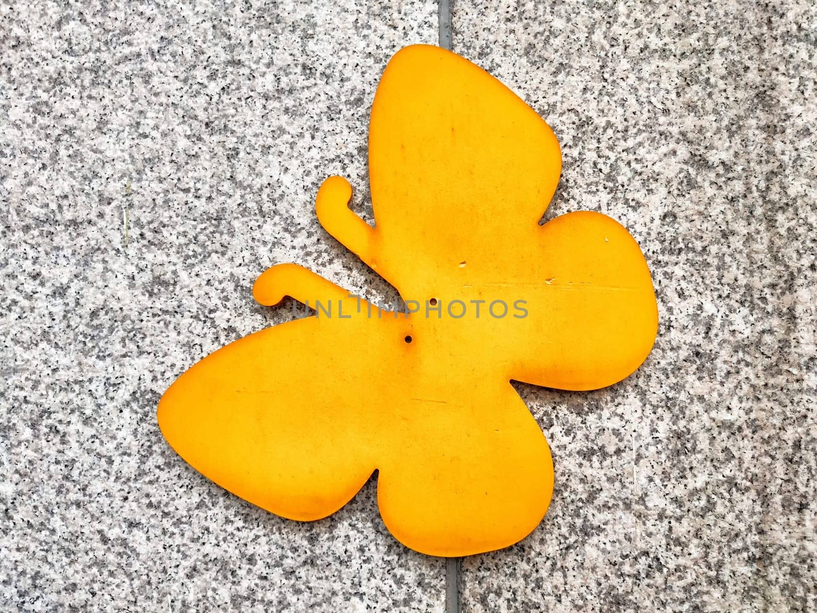 A vibrant yellow butterfly adorns a gray textured surface, creating an eye-catching display with ample copy space for creative use.