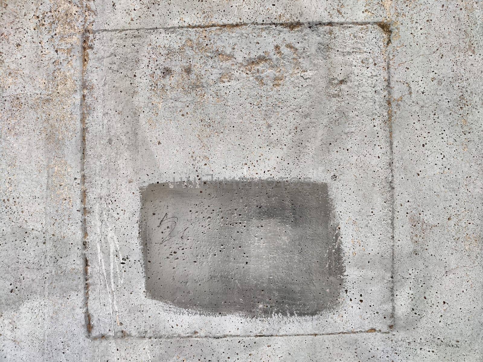 A weathered concrete wall displays a textured square frame with a faded area, providing ample space for promotional or informational text.