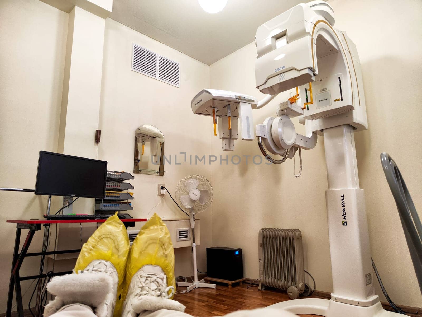 Kirov, Russia - November 28, 2024: Patient preparing for an X-ray examination in a hospital room equipped with advanced imaging technology and supportive equipment.