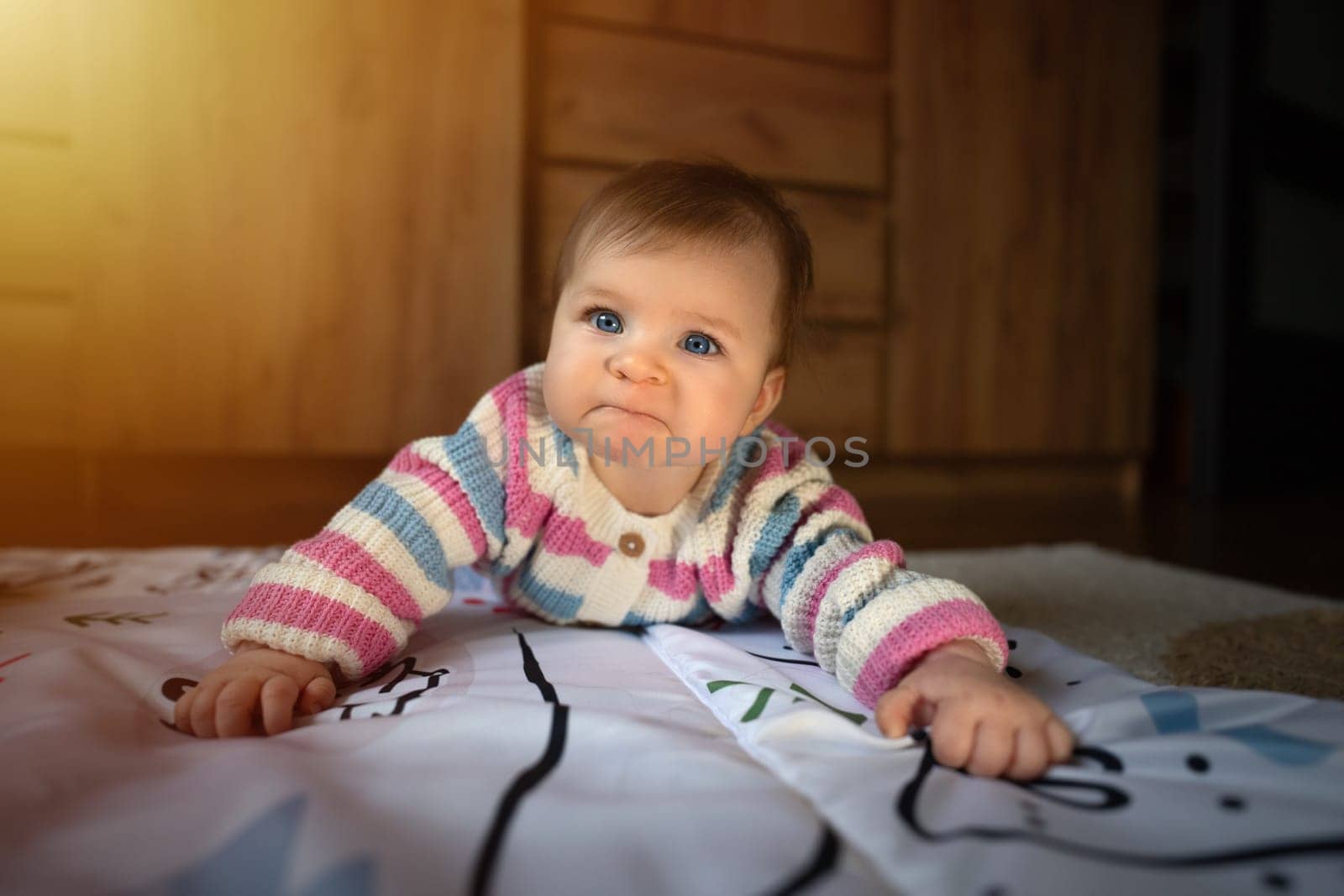 Grumpy cute baby girl lying on baby mat. Adorable kid portrait. 6 month old child. Childhood concept. High quality photo