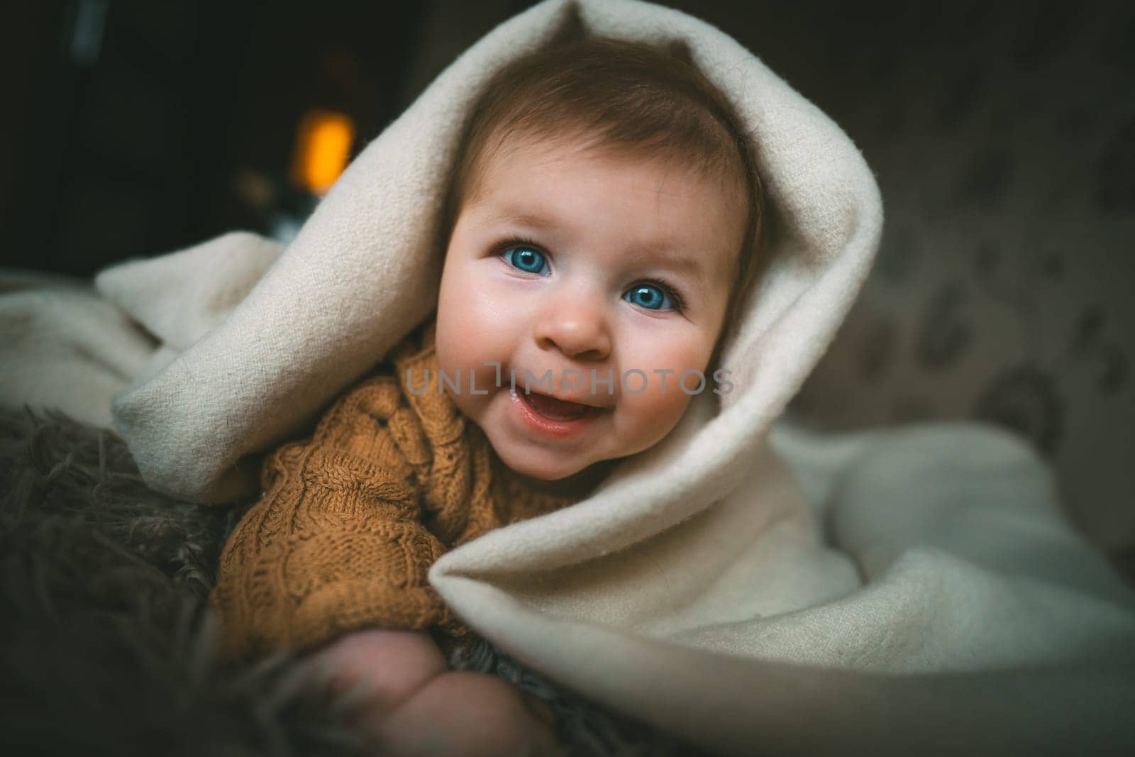 Smiling baby girl crawling on bed under the blanket. Adorable kid portrait. 5 month old child. Childhood concept. High quality photo