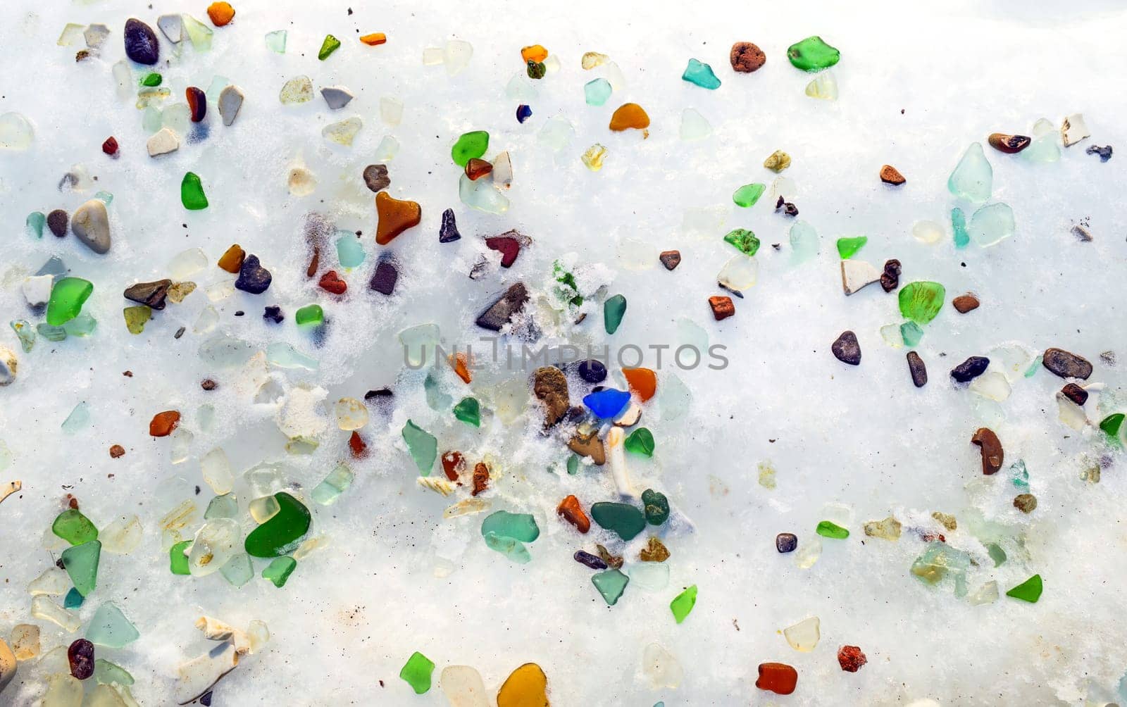 Background ice with multi-colored glass. Glass beach, Japanese sea, Russia.